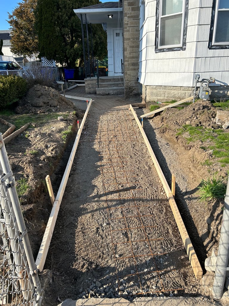 A gravel pathway under construction with wooden frame borders leading to a white mobile home entrance